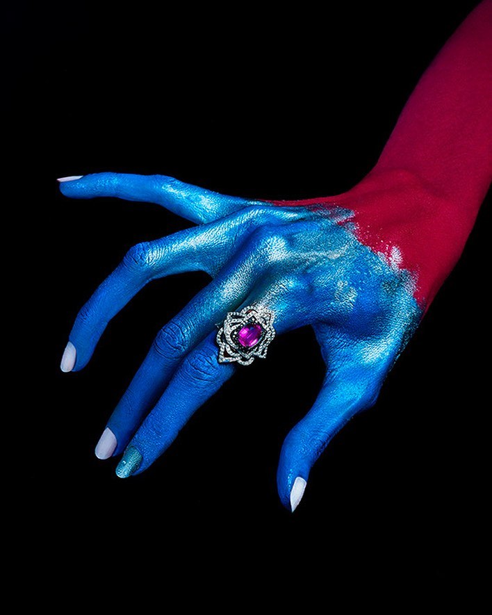 Painted hand art photographed against a dark background